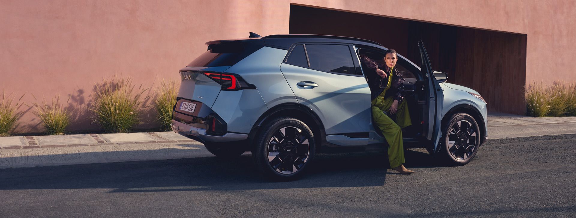 Kia Drive - Kia Sportage Hybrid in Seitenansicht mit Talent, das aus dem Beifahrersitz aussteigt